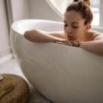 woman enjoying a calming bath as part of a full self-care routine