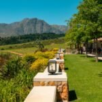 Scenic Stellenbosch wine estate with vineyards, mountains, and outdoor wine tasting at golden hour