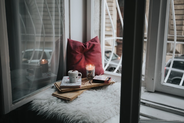 Cosy winter window seat with cushions, blanket and hot chocolate